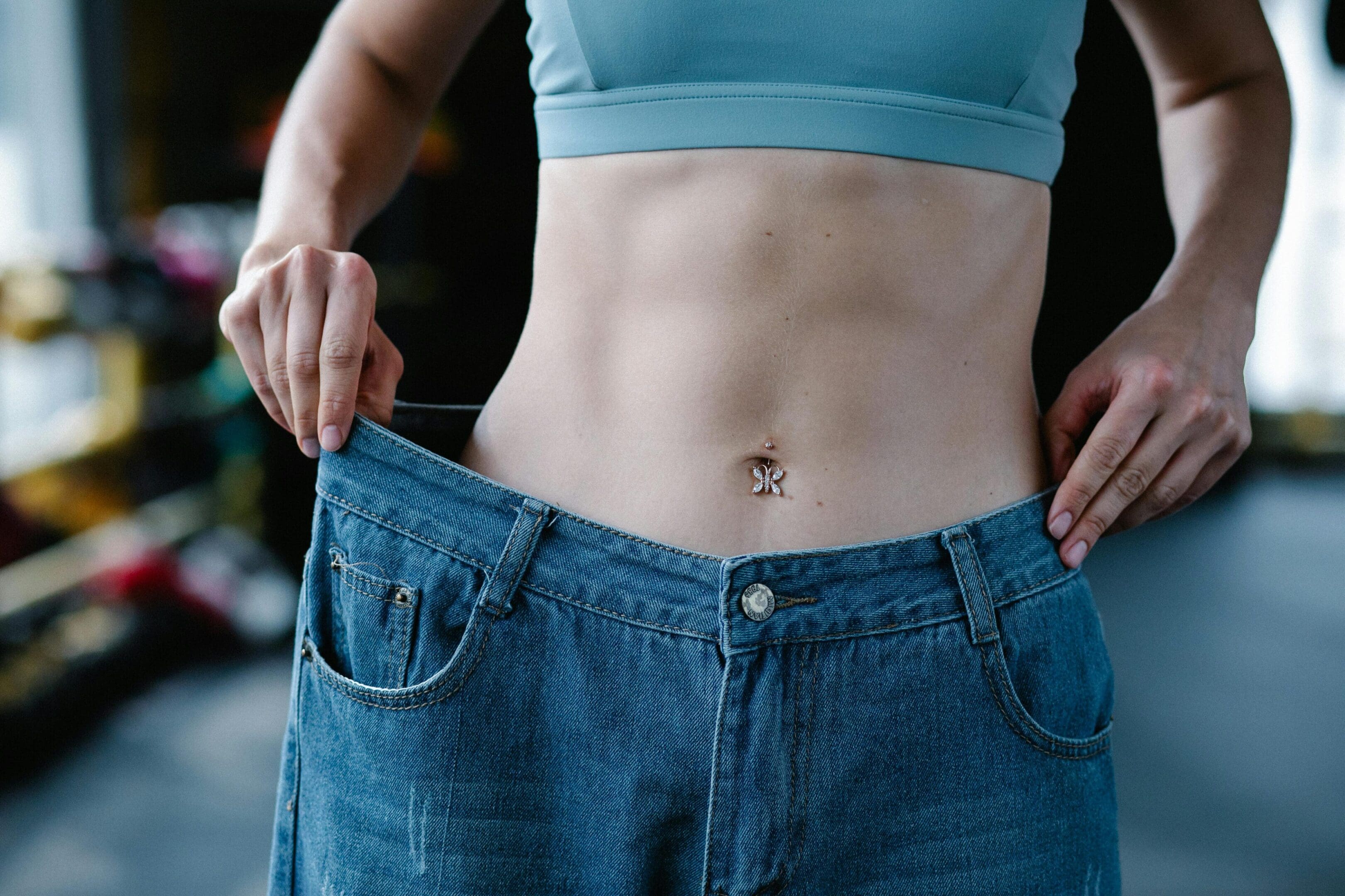 A woman is holding her jeans and showing off the waist.