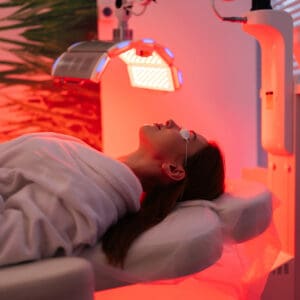 A woman laying down in the sun with red light shining on her.