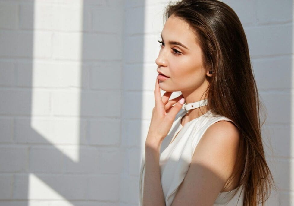 A woman in white shirt standing next to wall.